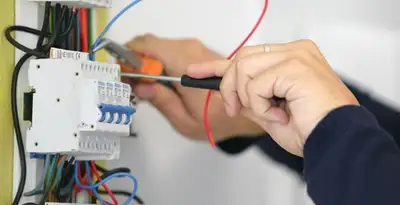 Electrician installing and adjusting circuit breakers in an electrical panel in San Antonio, TX