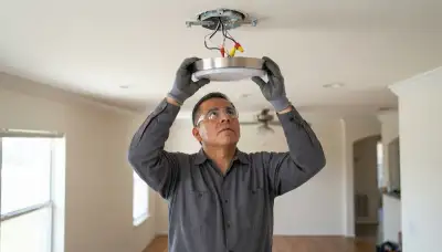 Electrician installing and wiring a ceiling light fixture in a San Antonio, TX home