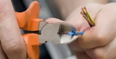licensed electrician performing precise wire cutting and preparation during electrical service in San Antonio, TX